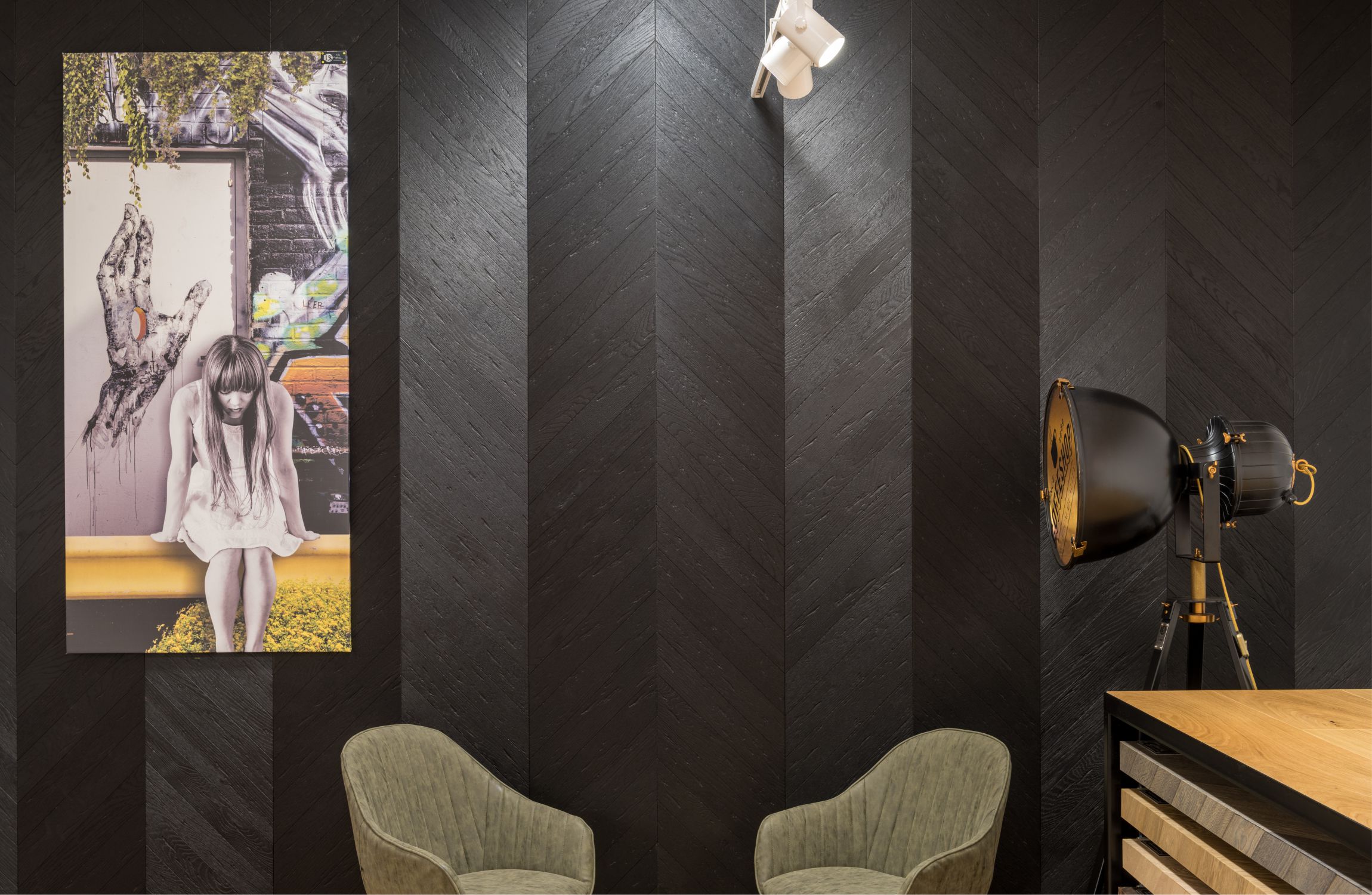 fekete halszálka fa falburkolat előtt matt fekete és bronz ipari tripodlámpa vászonképpel